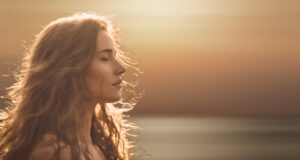 Psychology: strengthening self-esteem - woman strengthens her self-esteem - with closed eyes in front of sunset, appears calm, self-confident and in harmony with herself - low self-esteem in relationships - free initial session
